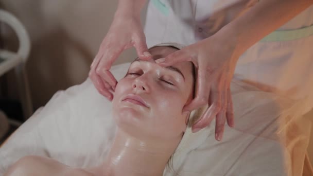 Professionele schoonheidsspecialiste maakt een complexe massage aan een jong meisje in het cosmetologie kantoor. — Stockvideo