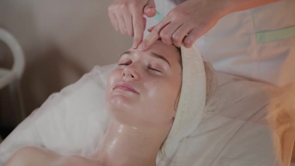 Professionele schoonheidsspecialiste maakt een complexe massage aan een jong meisje in het cosmetologie kantoor. — Stockvideo