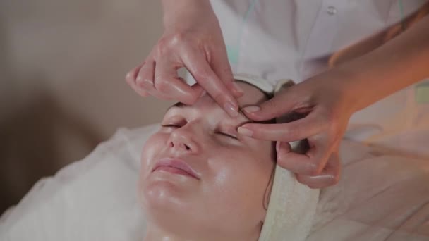 Professionele schoonheidsspecialiste maakt een complexe massage aan een jong meisje in het cosmetologie kantoor. — Stockvideo