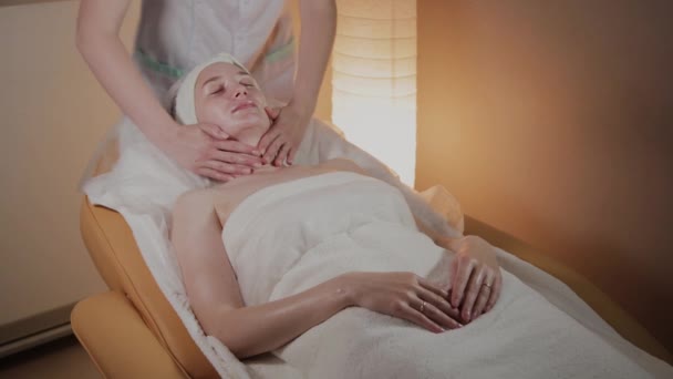 Профессиональный косметолог делает сложный массаж молодой девушке в косметологическом кабинете . — стоковое видео