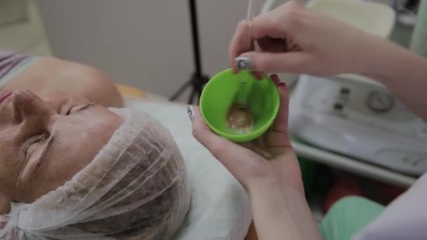 Kadın kozmetoloji stetik kozmetoloji kliniğinde makyaj maskesi karıştırır. — Stok video