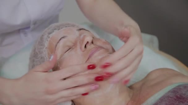 Kosmetikerin massiert ältere Frau in kosmetologischer Klinik. — Stockvideo