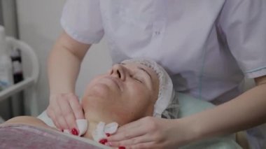 Güzellik uzmanı, bir kozmetoloji kliniğinde yaşlı bir kadının yüzünü yıkama işlemini gerçekleştirir.