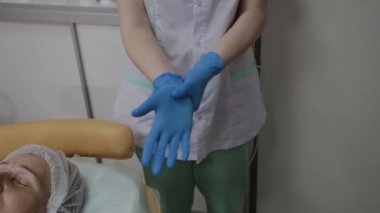 Profesyonel kozmetolojist prosedür için mavi lastik eldiven giyer.
