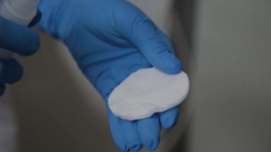 Beautician bir pamuk ped üzerine bir çözüm döker.