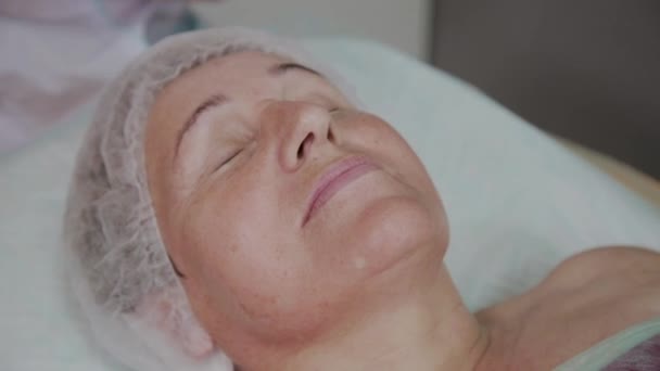An elderly woman is lying on a couch in a cosmetology clinic. — Stock Video