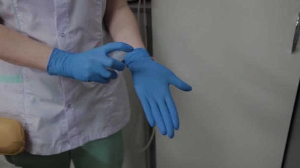 Een verpleegkundige in rubberen handschoenen spray een ontsmettingsmiddel op haar handen, close-up. Een verpleegkundige spuiten op hand desinfecterende oplossing. — Stockvideo