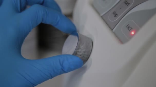 Un cosmetólogo profesional incluye un dispositivo para microcorrientes en una oficina de cosmetología . — Vídeo de stock