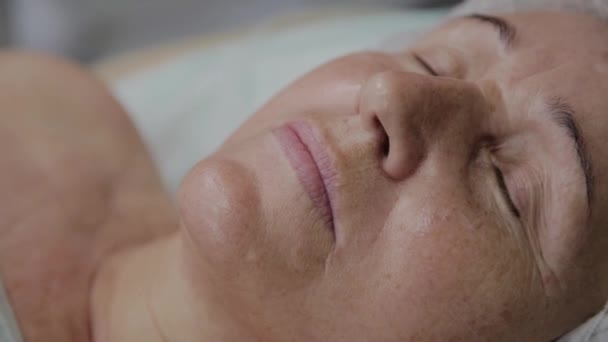 Una donna anziana è distesa su un divano in una clinica di cosmetologia . — Video Stock
