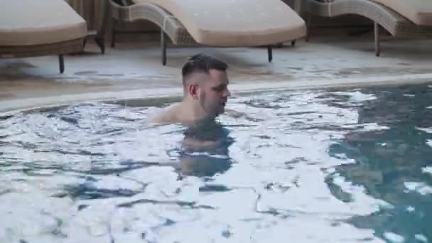 Hombre joven nada en la piscina cubierta . — Vídeo de stock