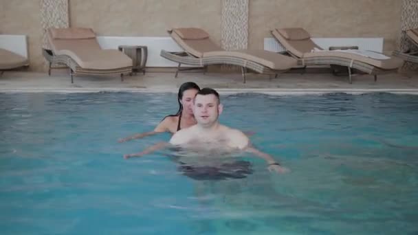 Młody mężczyzna i kobieta żartując i uśmiechając się w basenie. — Wideo stockowe