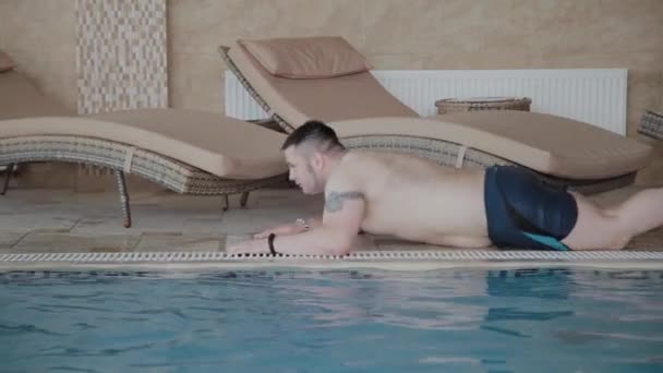 Egy fiatalember feltérképezi szélén a medence egy nő nevet vele. — Stock videók