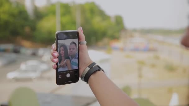 Een mooie vrouw en een vrolijke man nemen een selfie op de veranda van het restaurant. — Stockvideo