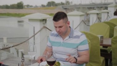 Açık terasta bir restoranda öğle yemeği alan genç erkek ve kadın.