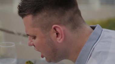 Genç bir adam açık terasta bir restoranda sebze li salata ile öğle yemeği yiyor. Sağlıklı gıda.