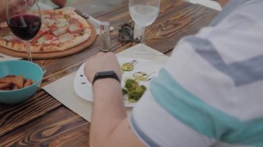 Genç bir adam açık terasta bir restoranda sebze li salata ile öğle yemeği yiyor. Sağlıklı gıda.