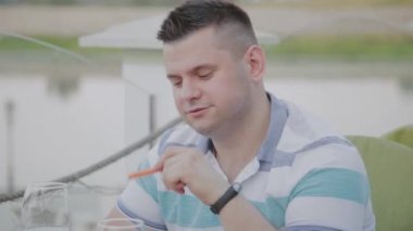 Genç bir adam açık terasta bir restoranda sebze li salata ile öğle yemeği yiyor. Sağlıklı gıda.