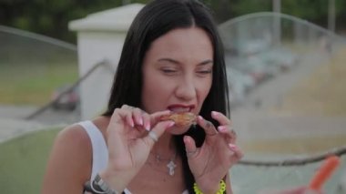 Bir kadın açık terasta bir restoranda kızarmış tavuk kanatları yemek ten hoşlanıyor.