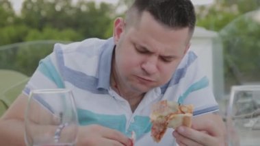 Bir adam hevesle bir restoranda abur cubur yiyor.