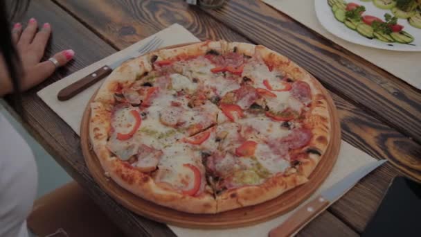 Fresh pizza on the table, a woman is preparing to eat it. — Stock Video