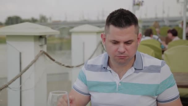 Ein junger Mann isst in einem Restaurant auf der offenen Terrasse zu Mittag mit Salat und Gemüse. gesunde Ernährung. — Stockvideo