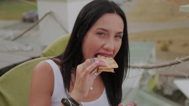 Mulher bonita comendo pizza no terraço de um restaurante . — Vídeo de Stock