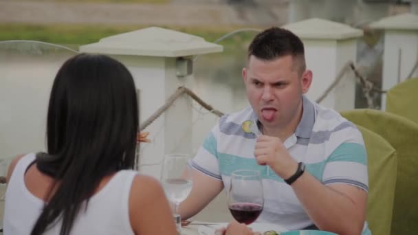 Hombre y mujer jóvenes almorzando en un restaurante en la terraza al aire libre . — Vídeo de stock