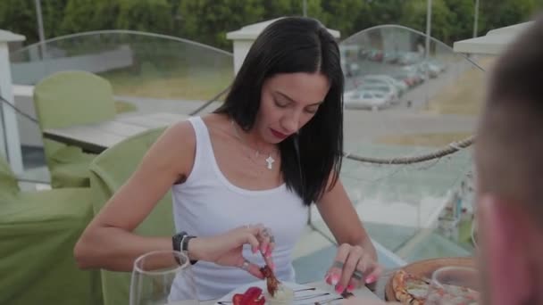 Uma mulher gosta de comer asas de frango fritas em um restaurante no terraço aberto . — Vídeo de Stock