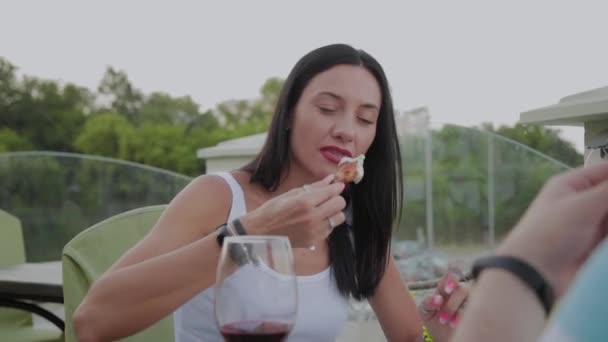 Жінка любить їсти смажені курячі крильця в ресторані на відкритій терасі . — стокове відео