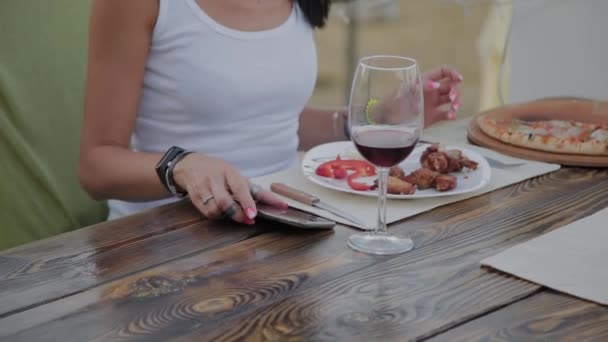 Hermosa mujer coge el teléfono de la mesa en el restaurante . — Vídeos de Stock