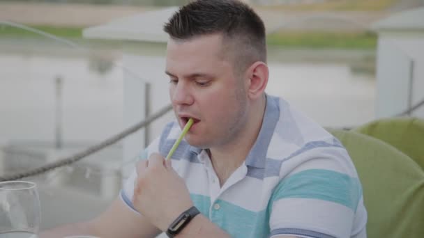 Um jovem está almoçando com uma salada com legumes em um restaurante no terraço aberto. Alimentos saudáveis . — Vídeo de Stock