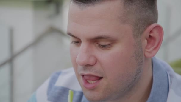 Un joven está almorzando con una ensalada con verduras en un restaurante en la terraza abierta. Alimento saludable . — Vídeo de stock