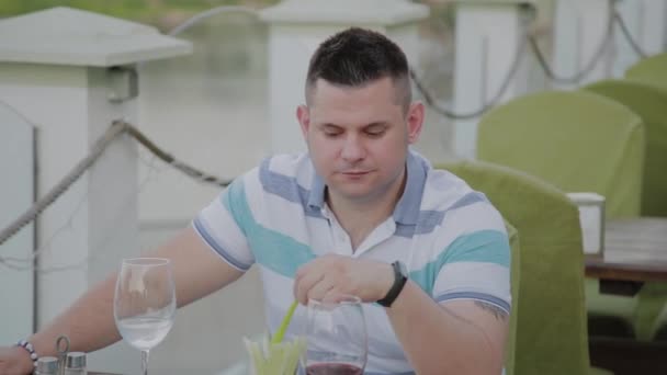 Un joven está almorzando con una ensalada con verduras en un restaurante en la terraza abierta. Alimento saludable . — Vídeo de stock