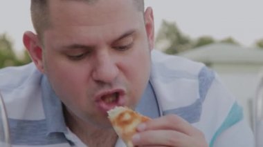 Bir adam hevesle bir restoranda abur cubur yiyor.