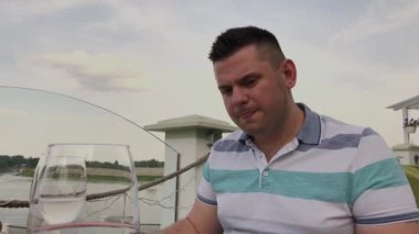 Genç bir adam açık terasta bir restoranda sebze li salata ile öğle yemeği yiyor. Sağlıklı gıda.