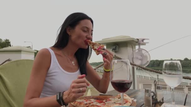 Gyönyörű nő, aki pizzát evett egy étterem teraszán. — Stock videók