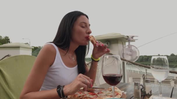 Mulher bonita comendo pizza no terraço de um restaurante . — Vídeo de Stock