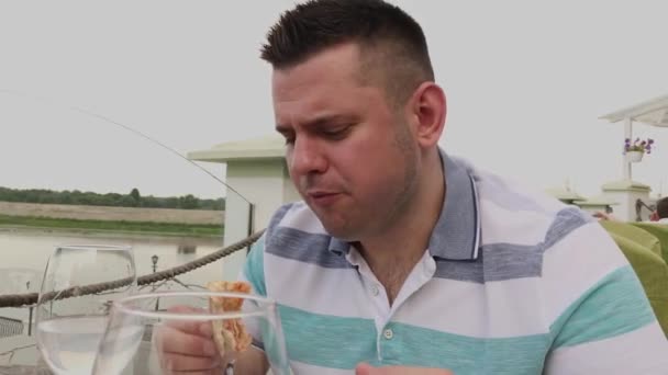 En man äter ivrigt skräpmat på en restaurang. — Stockvideo