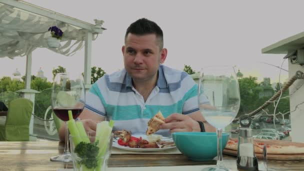 Un homme mange avec impatience de la malbouffe dans un restaurant . — Video