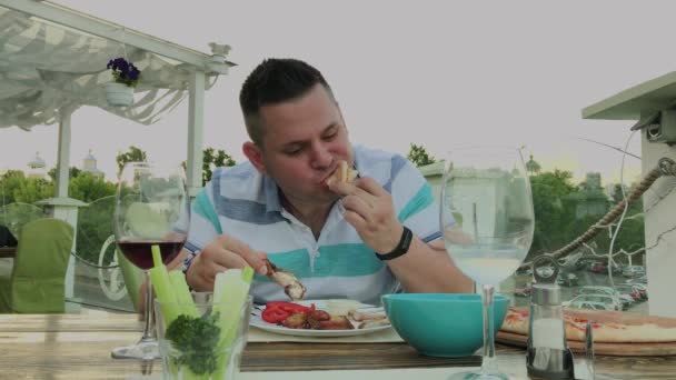 Ένας άνθρωπος τρώει με ανυπομονησία το πρόχειρο φαγητό σε ένα εστιατόριο. — Αρχείο Βίντεο