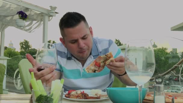 Un hombre come con entusiasmo comida chatarra en un restaurante . — Vídeo de stock