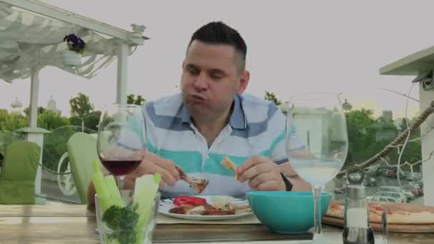 Un homme mange avec impatience de la malbouffe dans un restaurant . — Video