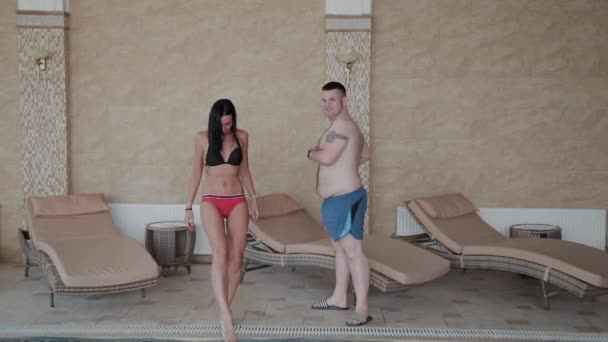 Красива жінка і чоловік стоять біля басейну . — стокове відео