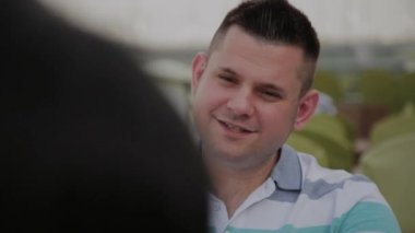 Güzel bir kadın ve bir adam açık bir terasta bir restoranda bir masada oturuyor.