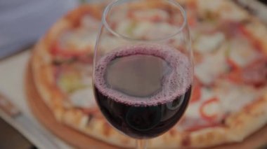 Taze pizza arka plan karşı masada kırmızı şarap bir bardak.