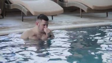 Genç adam kapalı havuzda yüzüyor.