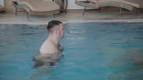 Молодий чоловік і жінка жартують і посміхаються в басейні . — стокове відео
