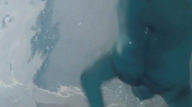 Neşeli komik adam havuzda yüzer. Havuzun dibinde aksiyon kamerası.