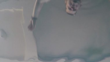 Neşeli komik adam havuzda yüzer. Havuzun dibinde aksiyon kamerası.