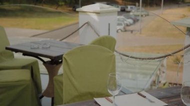 Güzel bir kadın açık terasta bir restoranda bir masada oturur ve masaya telefon koyar.